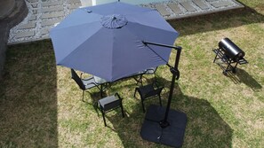Ein Patio mit Tisch und Stühlen unter einem großen Sonnenschirm.