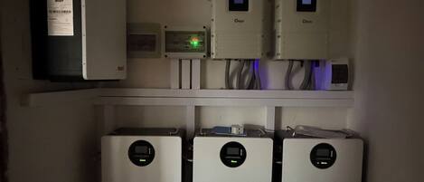 A utility room with three Must air conditioning units mounted on the wall, a control panel, and a labeled electrical box.