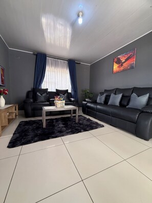 Ein modernes Wohnzimmer mit einem schwarzen Sofa, einem Couchtisch und einem großen Gemälde an der Wand.