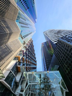 Een modern hooggebouw met een uniek architectonisch ontwerp, met glazen gevels die licht reflecteren en een combinatie van geometrische vormen.