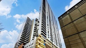 Ein hoher, moderner Wolkenkratzer mit einem markanten, ungewöhnlichen Design, umgeben von weiteren Hochhäusern.