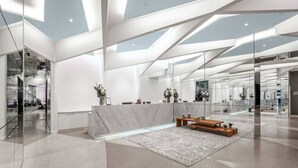 Un espace d’accueil moderne avec un comptoir en marbre, des cloisons en verre et un tapis à motifs.