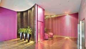 Eine moderne Lobby mit gewölbter Wand, einer Rezeption und Topfpflanzen.