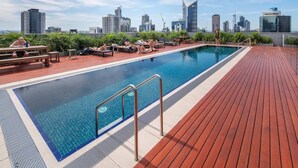 Une piscine sur le toit, avec la silhouette de la ville en arrière-plan.