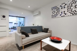 A modern living room with a sofa, a coffee table, and a decorative wall piece. - MHYL #CBD-Queen Victoria Market-Flagstaff 1BR Apt (Melbourne)