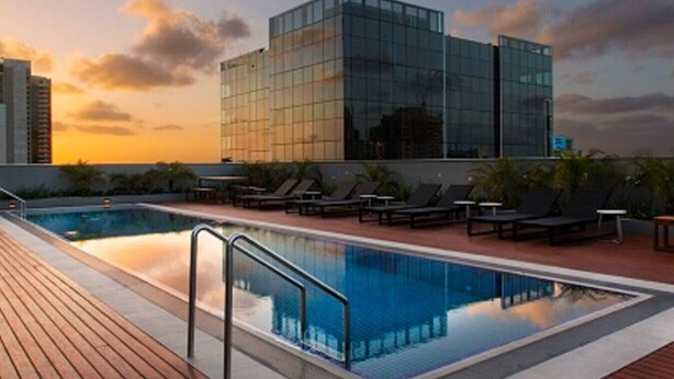 A rooftop pool area with lounge chairs and a glass building in the background. - MHYL # CBD stylish 1BR Apt with city view (Melbourne)