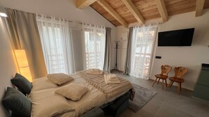 Une chambre à coucher avec un lit, des rideaux, une télévision et une chaise.