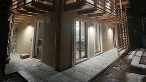 Un bâtiment en bois à deux étages, doté de balcons, de grandes fenêtres et d’une fondation en pierre.