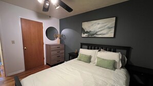 A bedroom with a bed, a dresser, a ceiling fan, a wall-mounted mirror, and a painting. - 1 bedroom condo walking distance to OHSU, close to VA, hiking trails! (Portland)