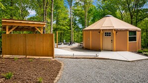 A yurt with a door and windows, a wooden fence, and a picnic table area.
