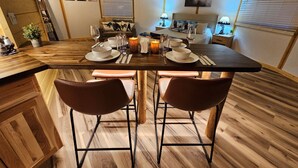A dining area with a wooden table set for two, a candle, and a painting of birds on the wall.
