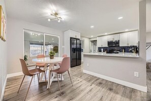 Una cocina moderna con armarios blancos, un refrigerador negro y un microondas de acero inoxidable.
