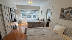 A spacious bedroom with a large bed, a smaller bed, and a window with blinds. - Serene country home in charming Volcano Village near the Volcano National Park. (Volcano)
