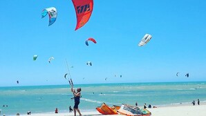 A beach with multiple kites and parasails in the air, and people on the sand. - Greenhouse Cumbuco, a cozy house 3 minutes from the village. (Caucaia)