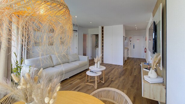 A modern living room with a sofa, a round wooden table, and a decorative hanging light. - Refúgio no Mar, Armação de Pêra (Silves)