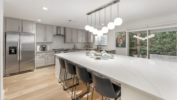 A modern kitchen with a large island, stainless steel appliances, and a view of greenery outside. -  Art Inspired Coastal Retreat in Ponte Vedra Near Beach Ideal for Families (Nocatee)