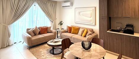 A modern living room with a dining area, a sofa set, a coffee table, and a kitchen area with wooden cabinets.