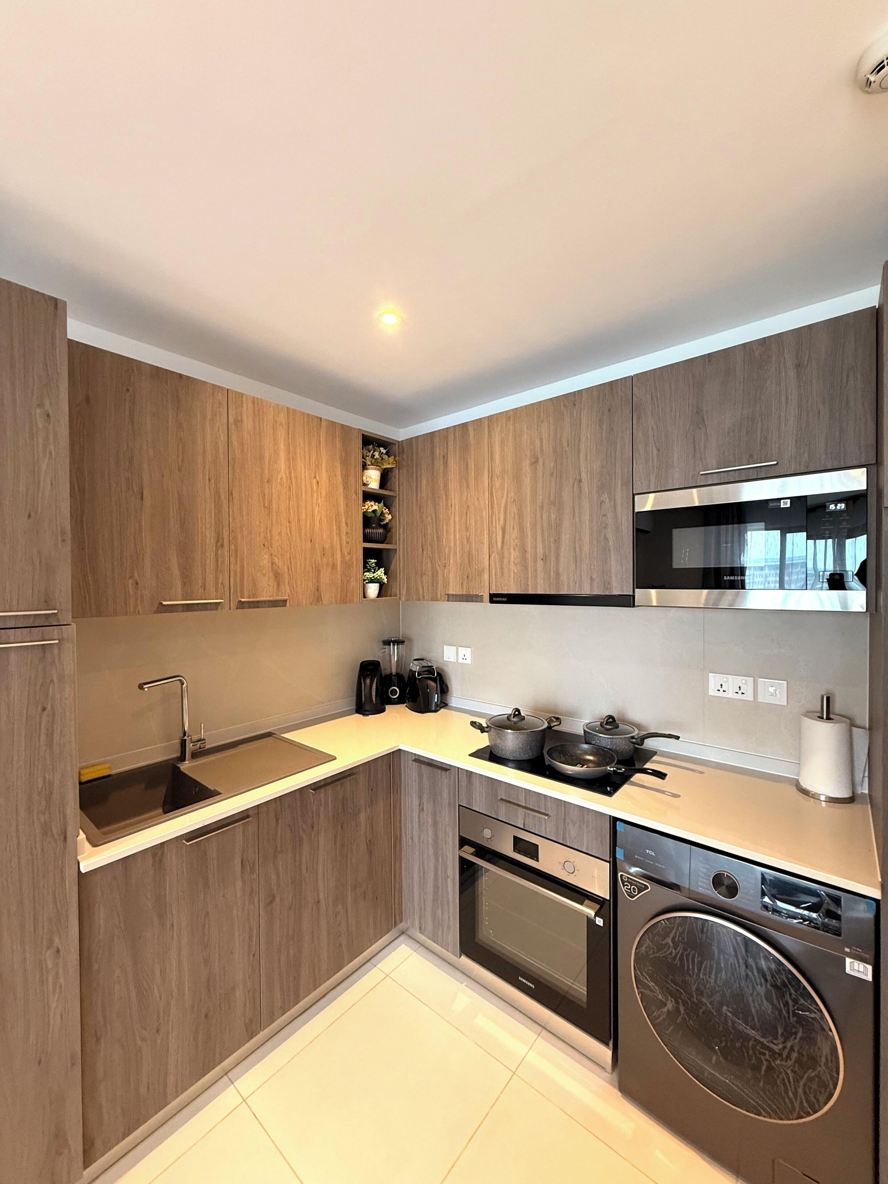 A modern kitchen with wooden cabinets, a stainless steel microwave, a built-in oven, and a dishwasher.