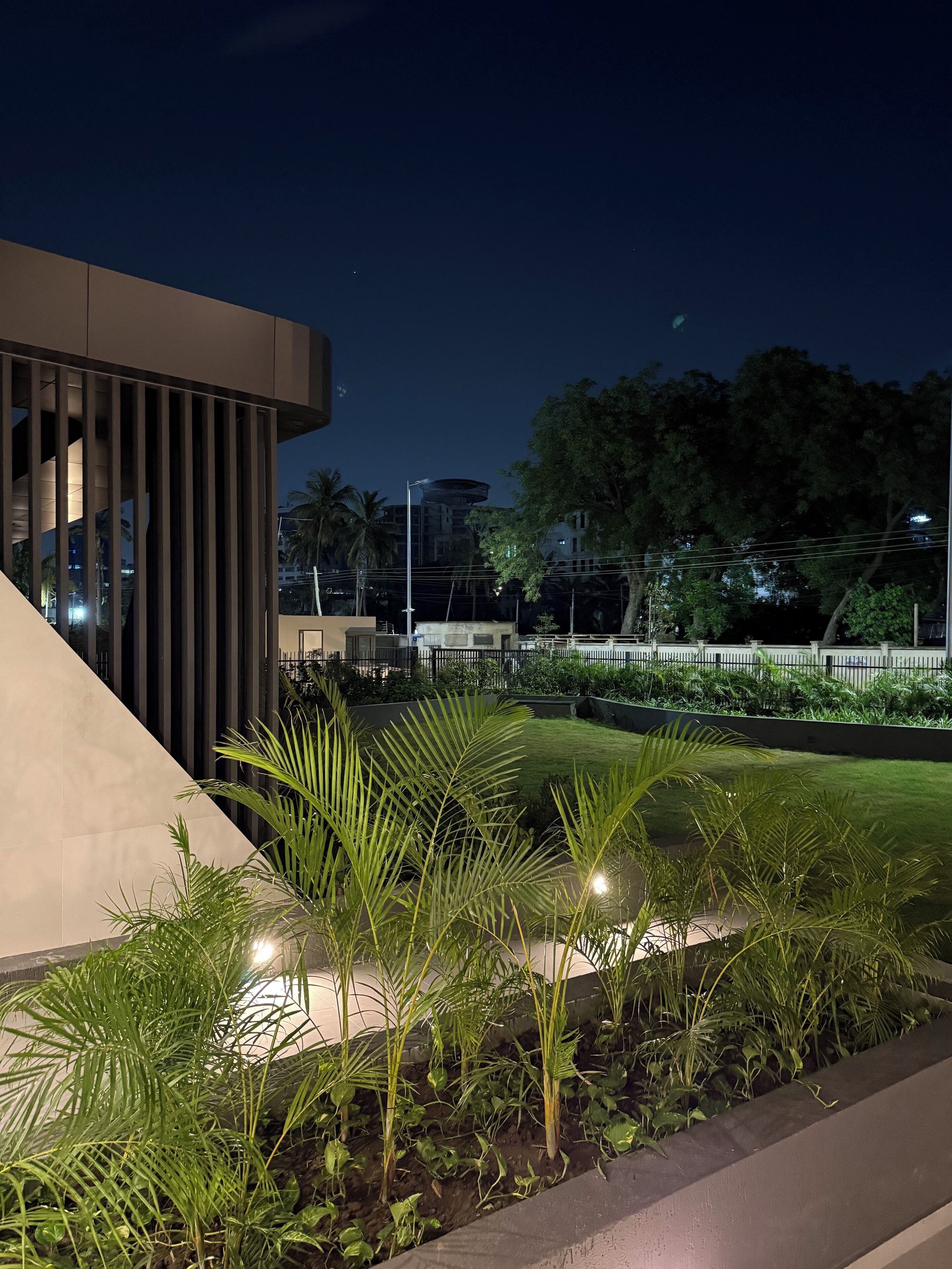 A modern building with a sloped roof and a landscaped garden with palm trees.