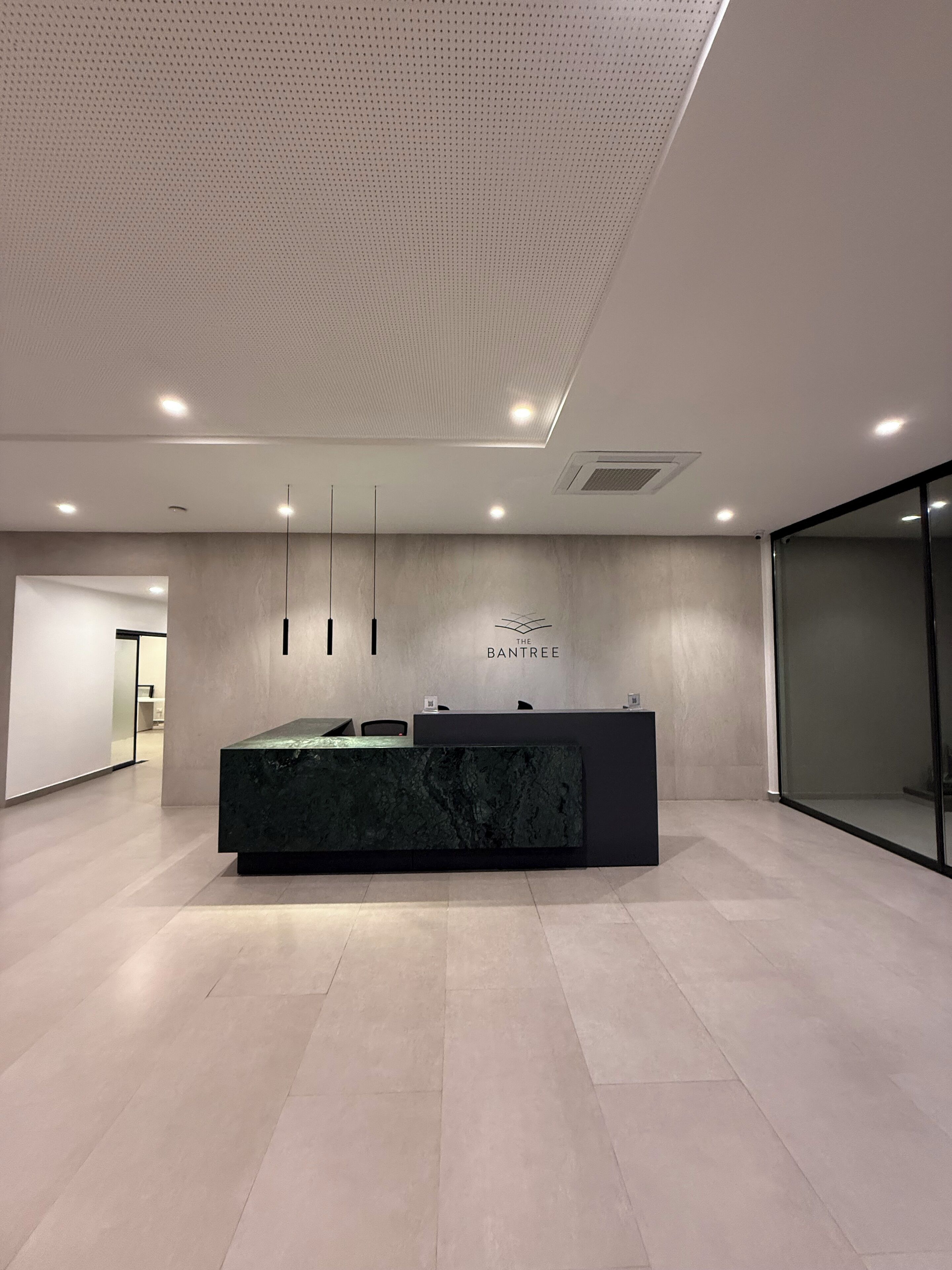 A modern reception area with a dark marble counter, pendant lighting, and a wall-mounted sign reading "THE BANTREE".
