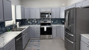 Eine moderne Küche mit grauen Schränken, Edelstahlgeräten und einer Marmor-Spritzschutzwand.