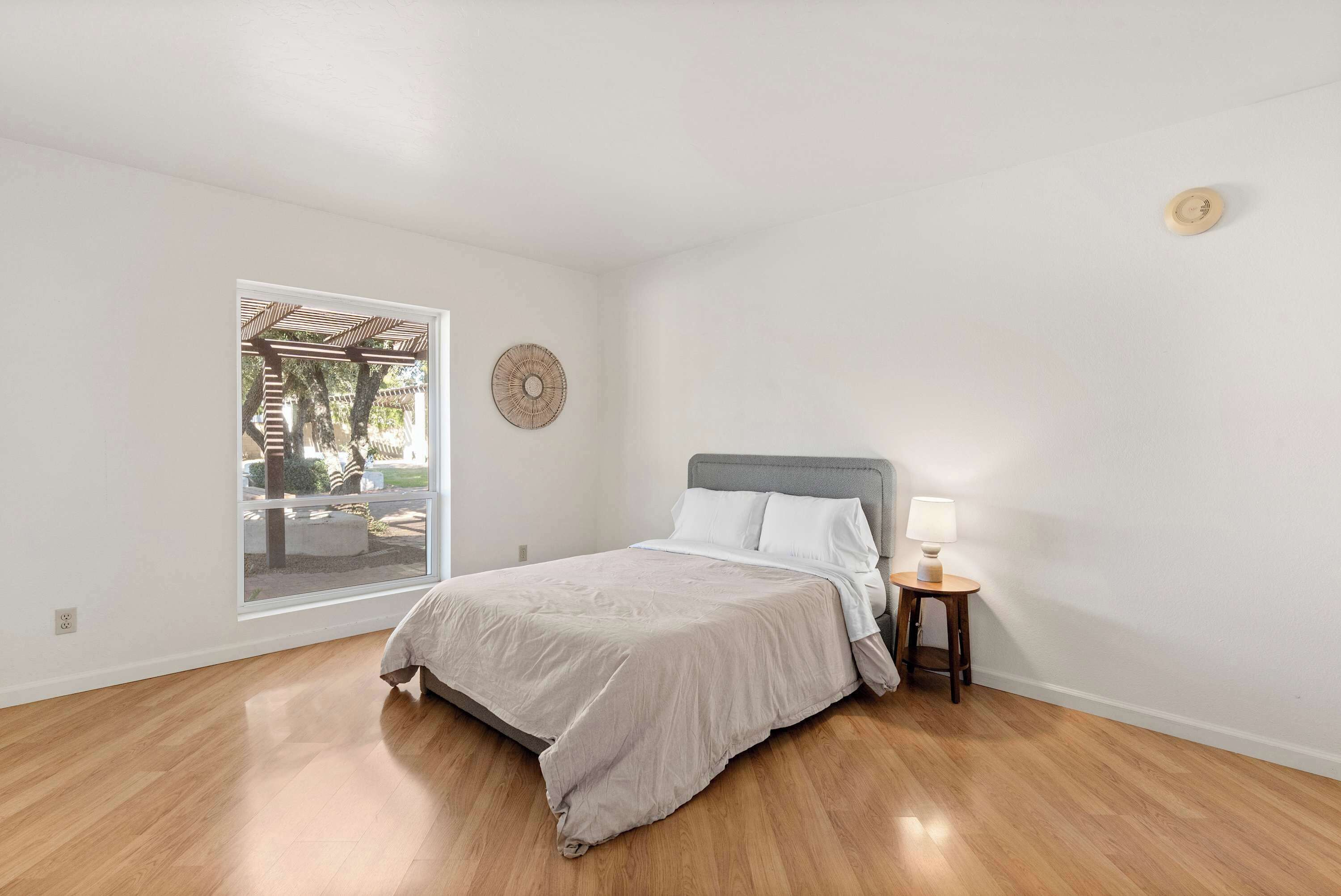 Una camera da letto con un letto, un comodino con una lampada, una finestra e un elemento decorativo al muro.