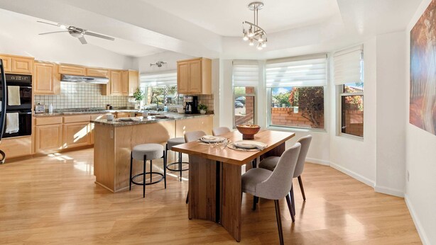 Una cocina moderna con armarios de madera, una isla central y un comedor con sillas.