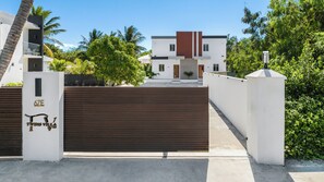 A gated entrance to a modern building with a white facade, a brown gate, and a sign indicating 'TWINSVILLA'. - Twins Villa - Mellizo A - Wonderful 2-bedroom villa with AC in Long Bay Hills (Long Bay Hills)