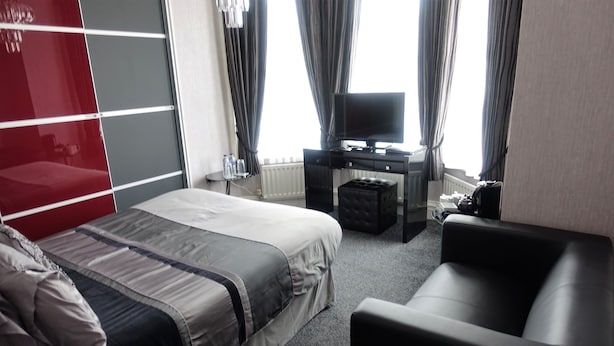 Una habitación de hotel con una cama, un escritorio con computadora, televisor y sofá.