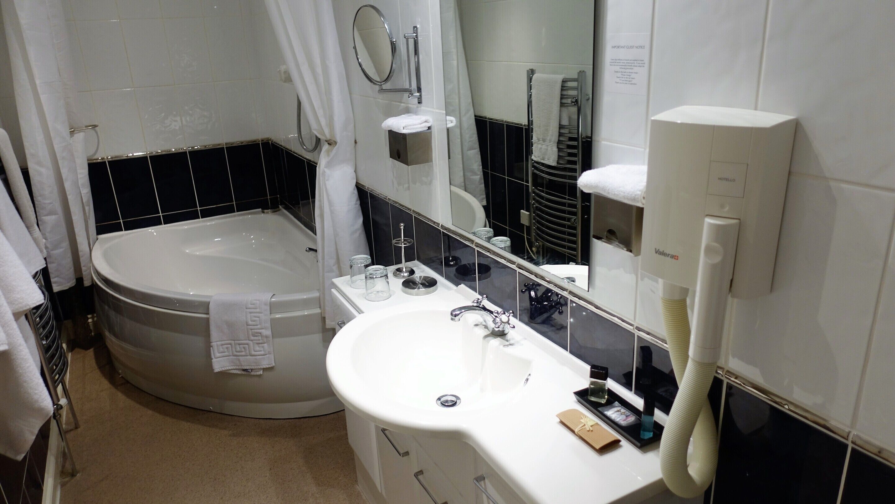 A bathroom with a bathtub, a sink, a mirror, and a towel rack.