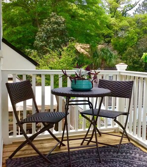 Eine überdachte Terrasse mit einem runden Tisch und zwei Stühlen, umgeben von einem weißen Geländer.