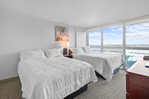 A hotel room with two beds, a nightstand with a lamp, a painting, and a large window with a view of the water. - Cozy Apartment at the Heart of Fort Myers (Fort Myers)