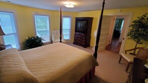 Une chambre à coucher avec un grand lit, une commode, un téléviseur et un fauteuil.