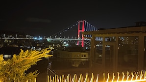 A night view of a cityscape with a prominent bridge illuminated in red and white lights. - Stylish apartment with Bosphorus view (İstanbul)