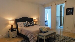 Un dormitorio con una cama, mesitas de noche, un banco y una alfombra.