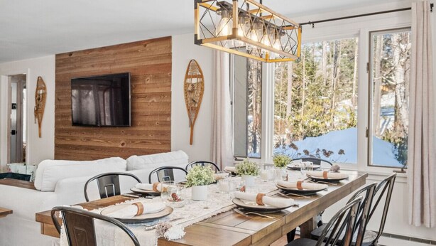 A dining area with a wooden table set for six, surrounded by chairs. A modern pendant light hangs above the table. - Jamaica Chalet: 3 Kings + Arcade | Starlink (Jamaica)
