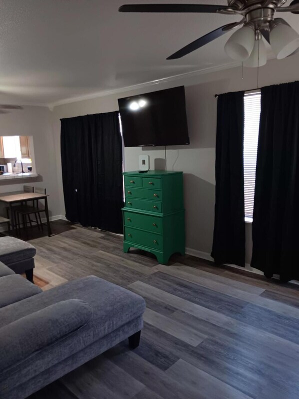 A modern living room with a grey sofa, a green dresser, and a ceiling fan.