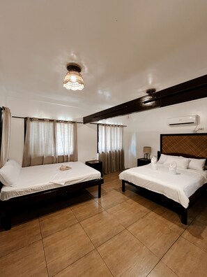 A hotel room with two beds, a chandelier, an air conditioning unit, and a wooden ceiling beam. - Aggehanan Beach Resort (General Luna)