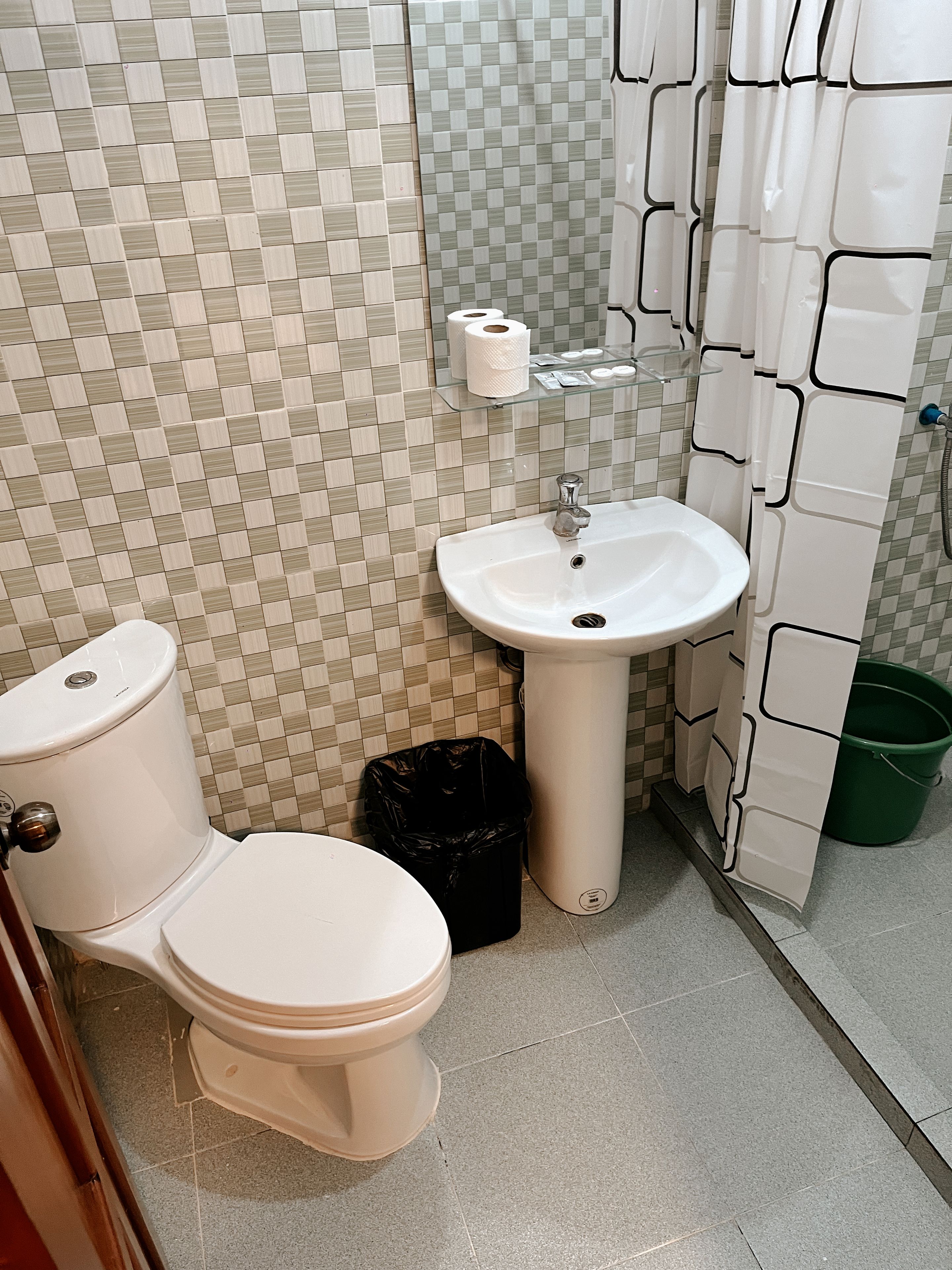 A bathroom with a toilet, sink, and a trash bin.