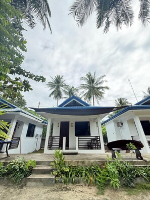 A bungalow with a blue roof, surrounded by palm trees and greenery. - Aggehanan Beach Resort (General Luna)