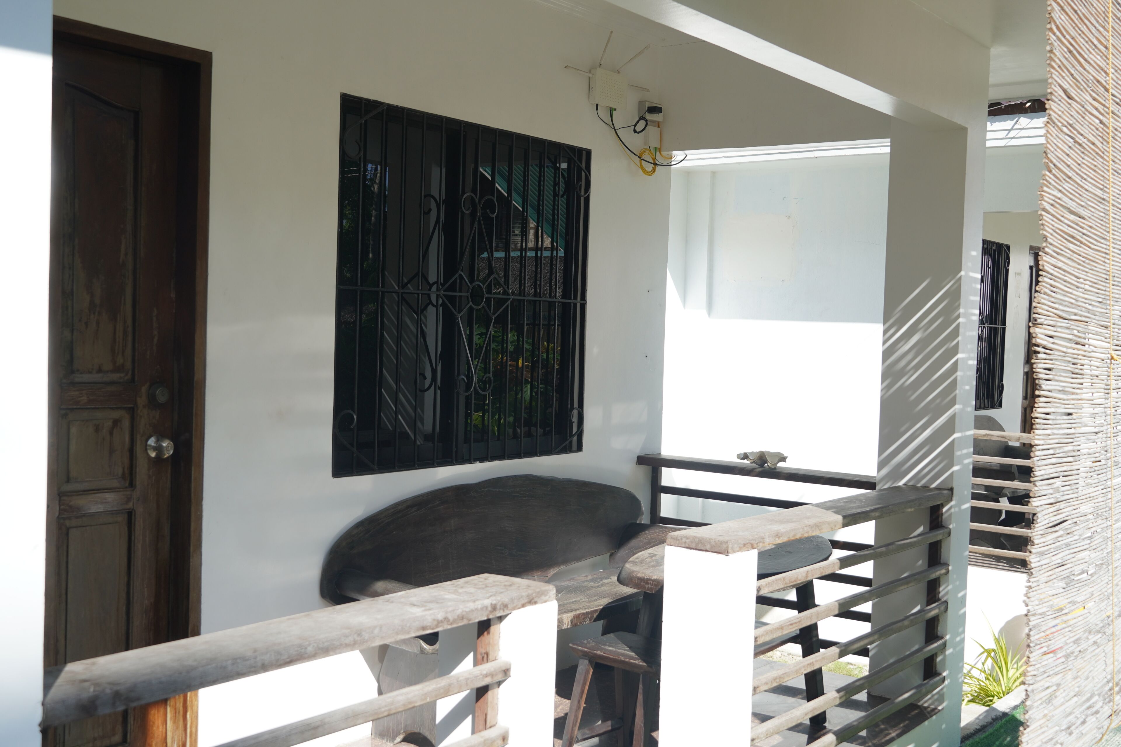A wooden door, a bench, a wall-mounted artwork, a window, and a staircase railing.