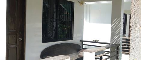 A wooden door, a bench, a wall-mounted artwork, a window, and a staircase railing.