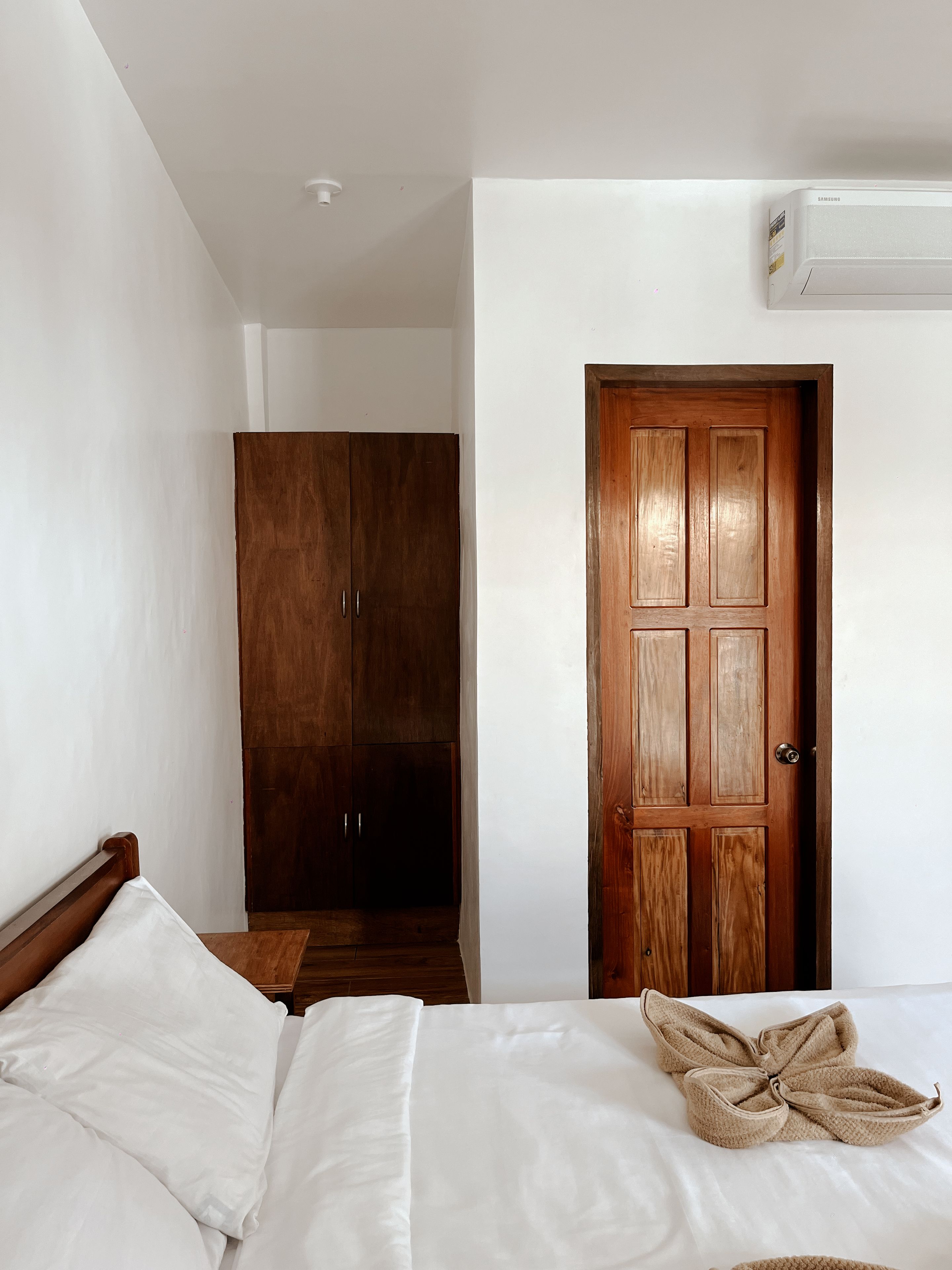 Quarto com uma cama, guarda-roupa e porta.