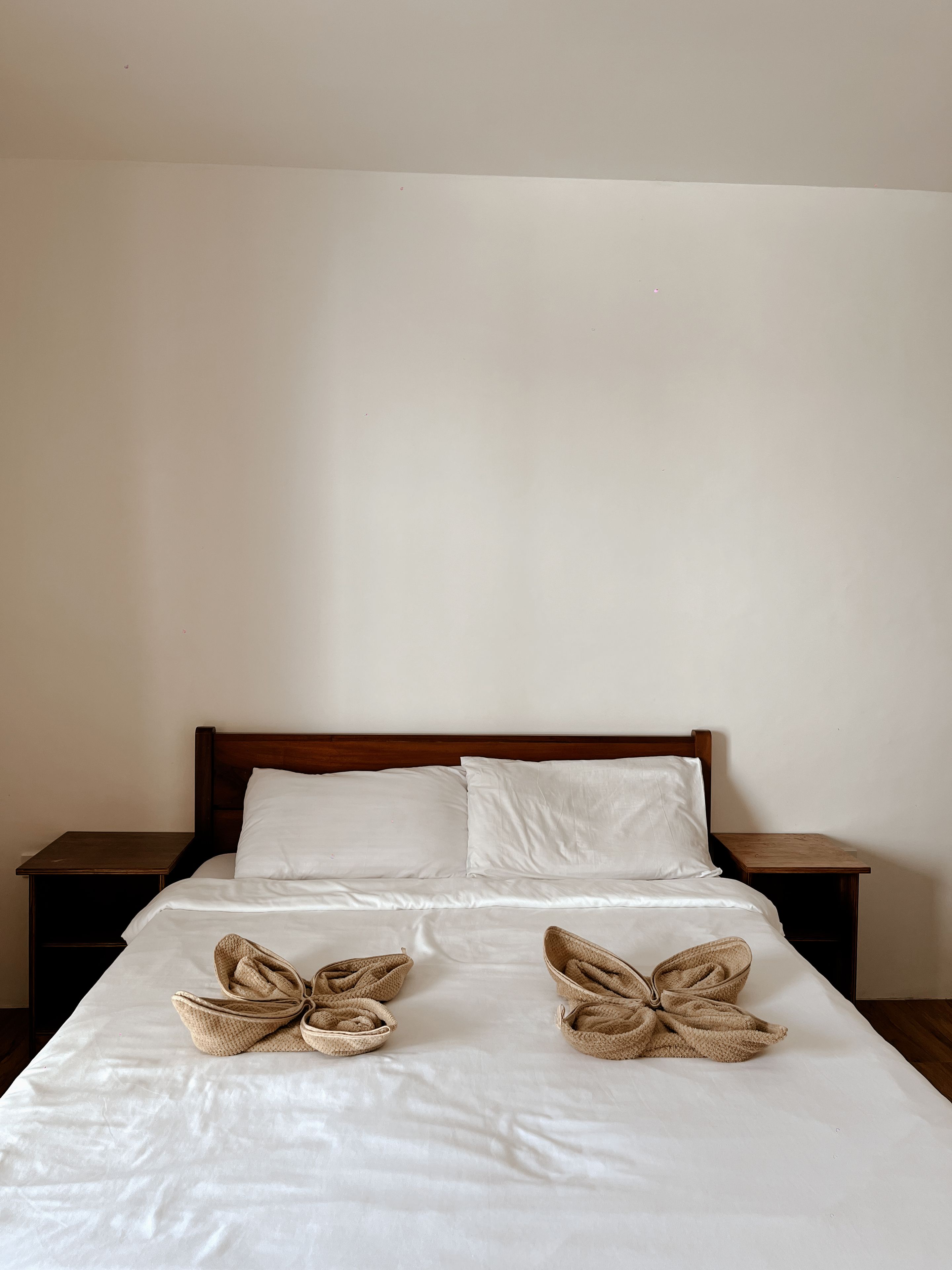 Ein Bett mit weißen Leinentüchern und zwei gewebten Körben darauf.