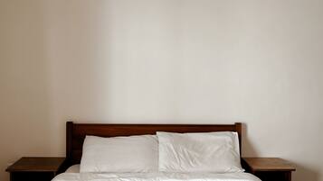 A bed with white linens and two woven baskets placed on it.