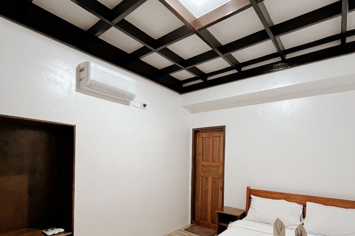 A bedroom with a wooden bed, a wardrobe, a door, and a skylight.