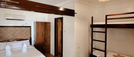 Un dormitorio con una cama, una litera, un armario de madera y una lámpara en el techo.