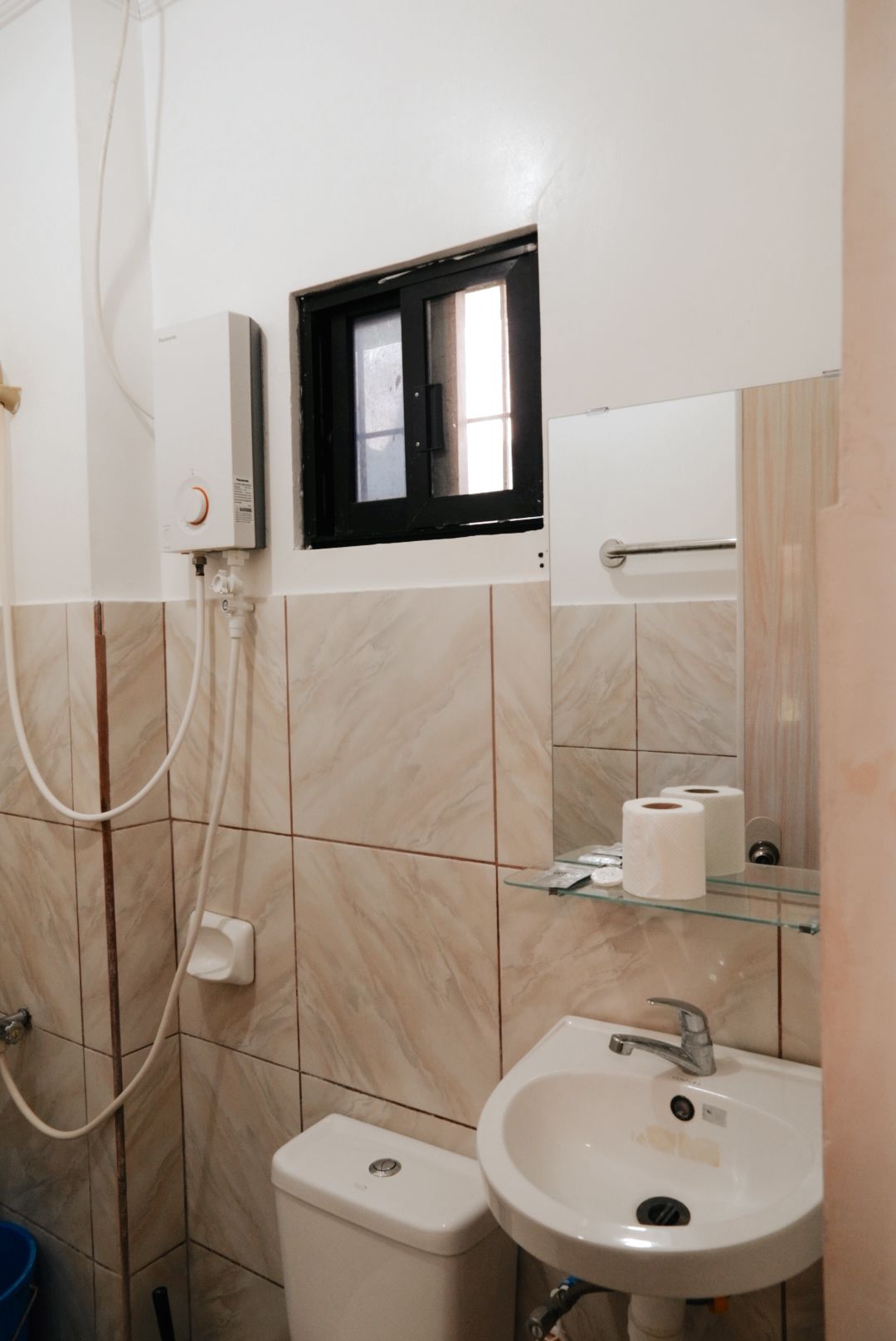 A bathroom with a toilet, sink, and a window with a black frame.