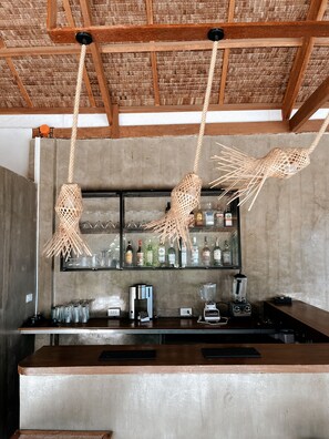 A bar area with a concrete countertop, a coffee machine, a blender, and a shelf with bottles. - Aggehanan Beach Resort (General Luna)
