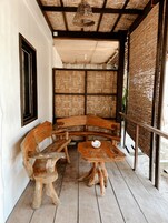 A rustic wooden bench and table set in a covered outdoor area with a woven ceiling and walls.